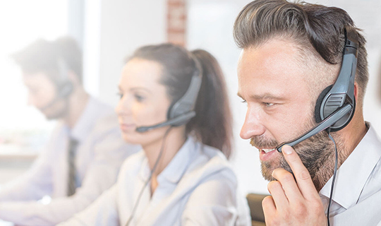Cuatro personas con headsets responden llamadas de clientes